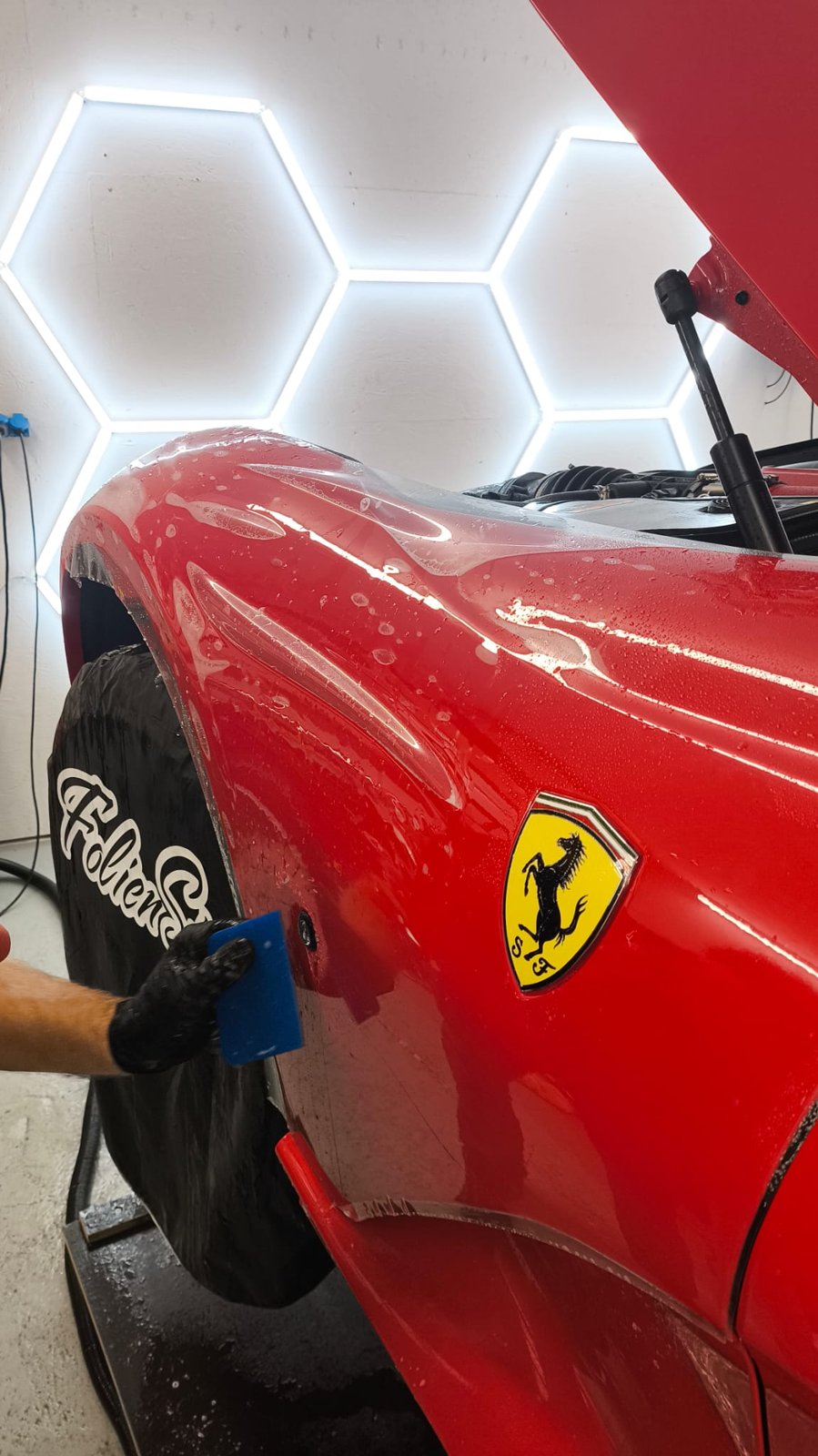 Steinschutzfolie wird an der Seitenpartie eines roten Ferrari aufgerakelt