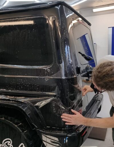Steinschutzfolie wird am Heck einer schwarzen Mercedes G-Klasse angebracht